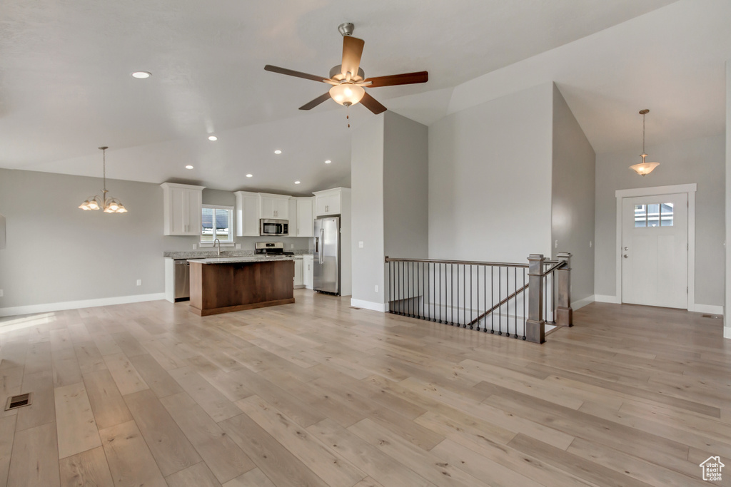 Kitchen featuring open floor plan, light wood-style floors, white cabinetry, high vaulted ceiling, and appliances with stainless steel finishes