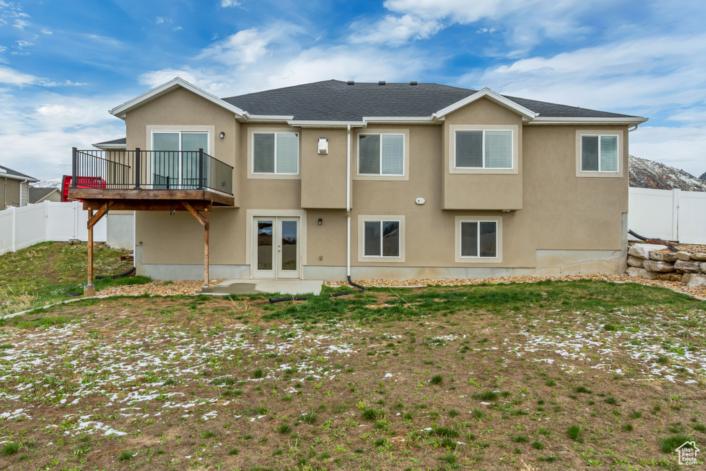 Rear view of house featuring stucco siding, a fenced backyard, french doors, and a deck