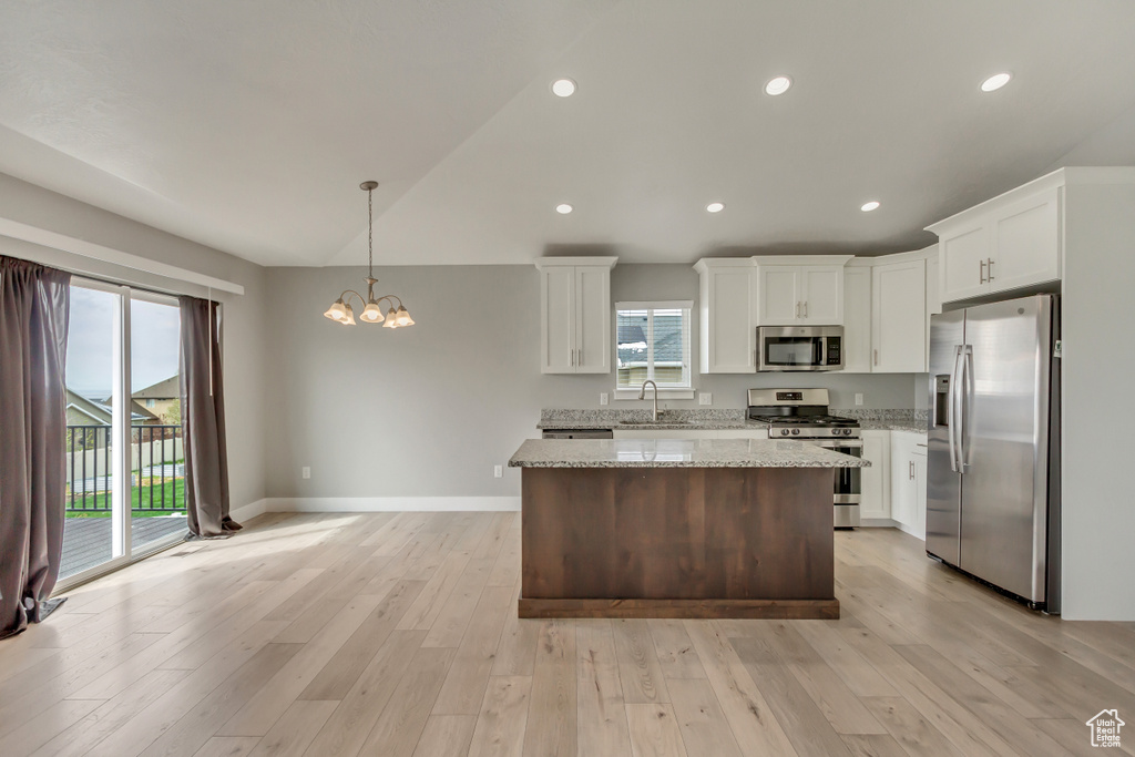 Kitchen with appliances with stainless steel finishes, a sink, white cabinetry, and a kitchen island