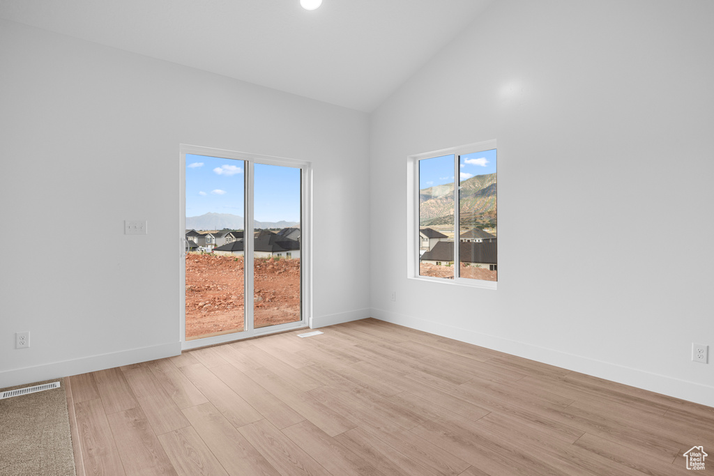 Spare room with light wood finished floors, healthy amount of natural light, and high vaulted ceiling