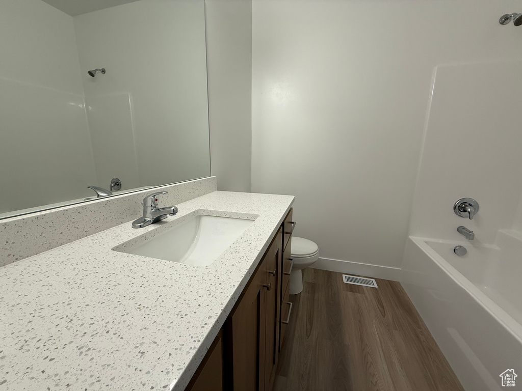 Full bath featuring vanity, wood finished floors, toilet, and shower / bath combination