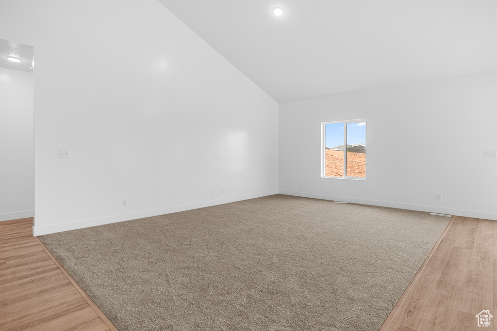 Additional living space with light wood-type flooring, high vaulted ceiling, and recessed lighting