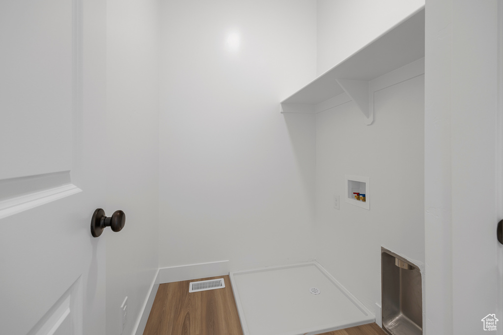 Washroom with hookup for a washing machine and wood finished floors