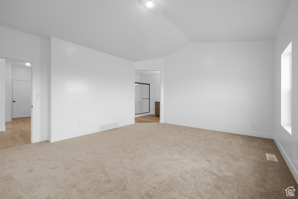 Empty room with carpet floors and lofted ceiling