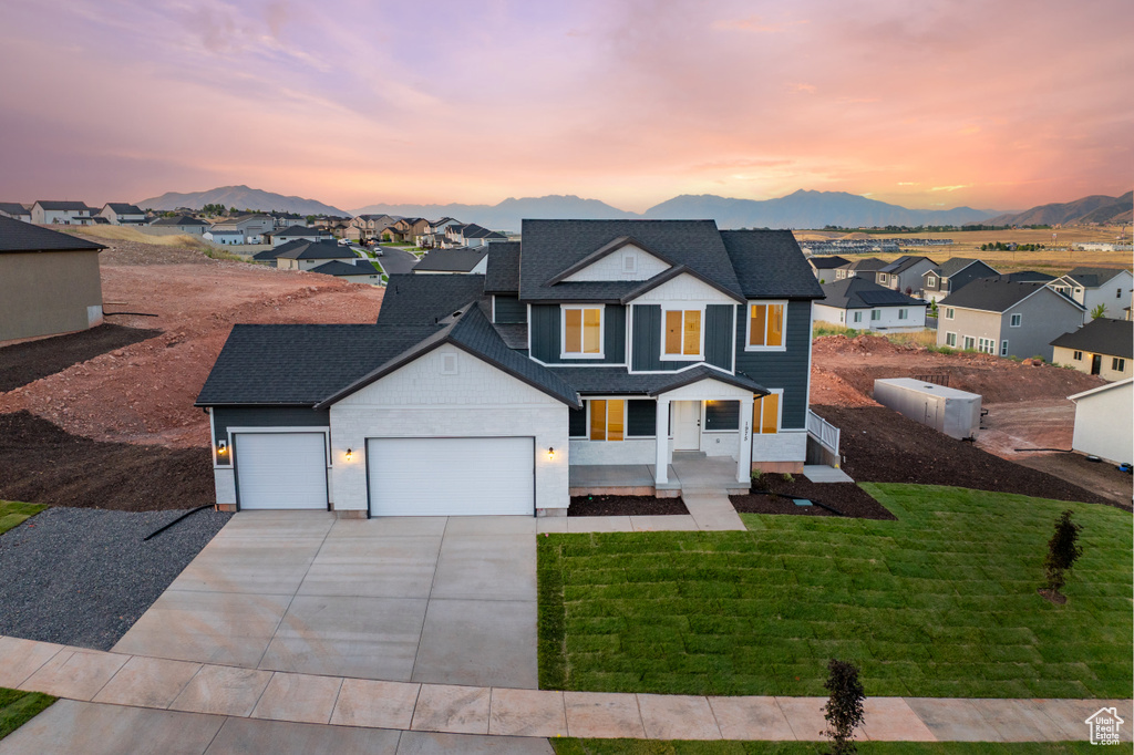Traditional home with a garage, driveway, a residential view, a mountain view, and roof with shingles