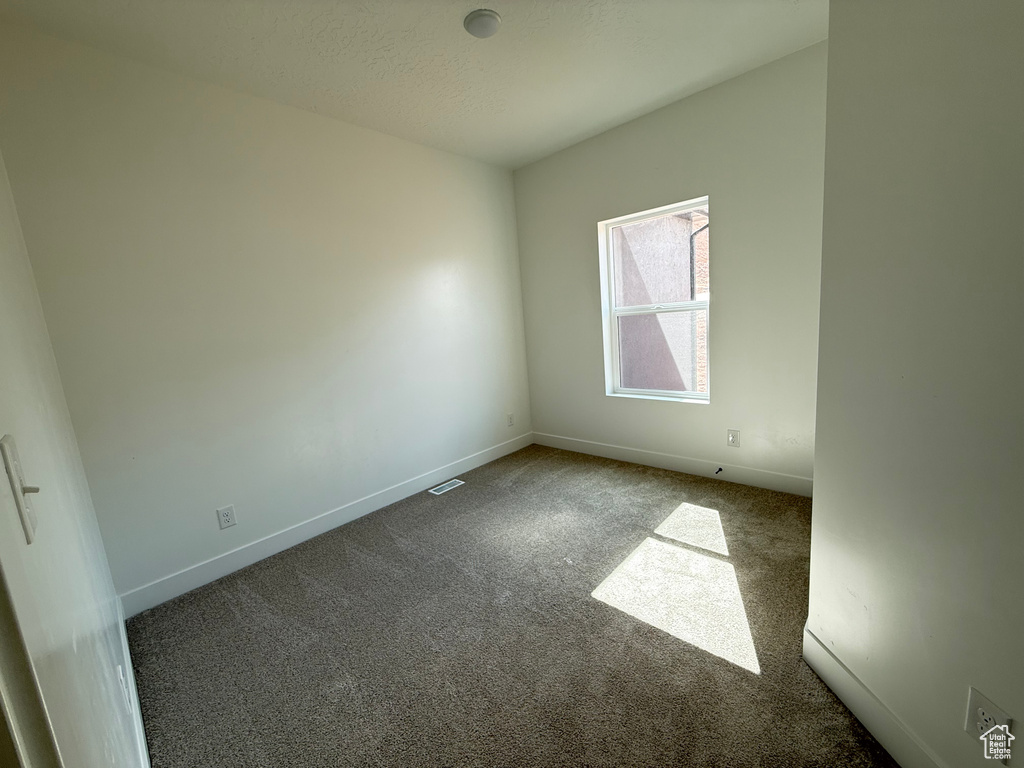 Spare room featuring carpet flooring and baseboards