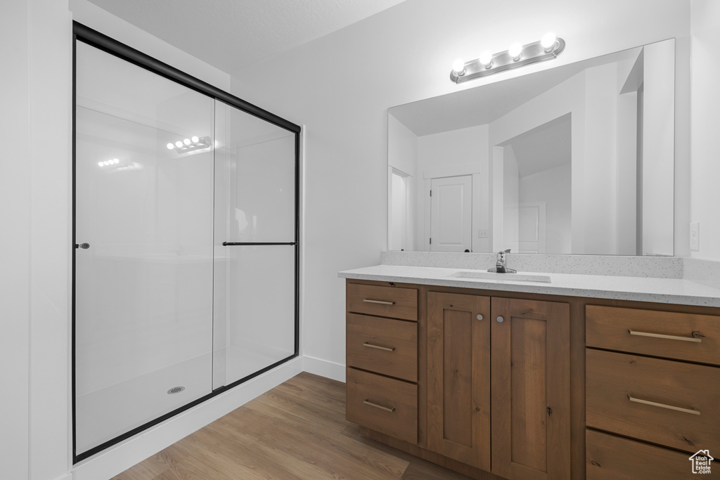 Full bathroom featuring vanity, wood finished floors, and a stall shower