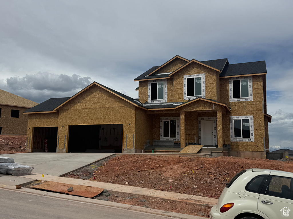 View of front of home featuring covered porch, concrete driveway, and a garage