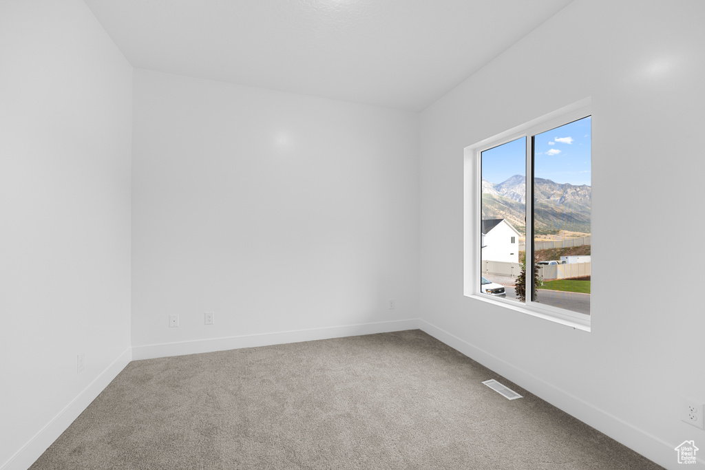 Carpeted spare room with baseboards and a mountain view