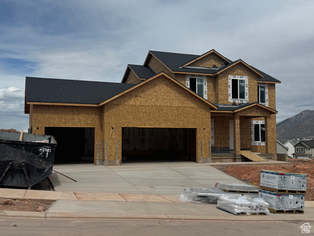 View of front of home featuring an attached garage, driveway, a mountain view, and roof with shingles