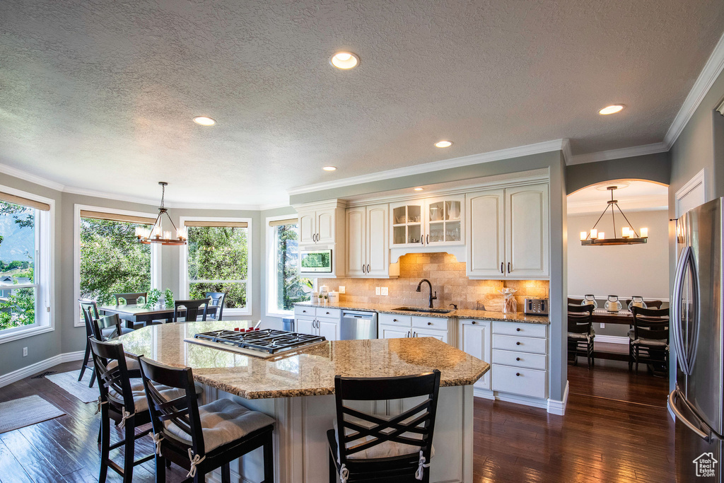 Kitchen featuring a chandelier, appliances with stainless steel finishes, a kitchen island, dark wood finished floors, and a textured ceiling