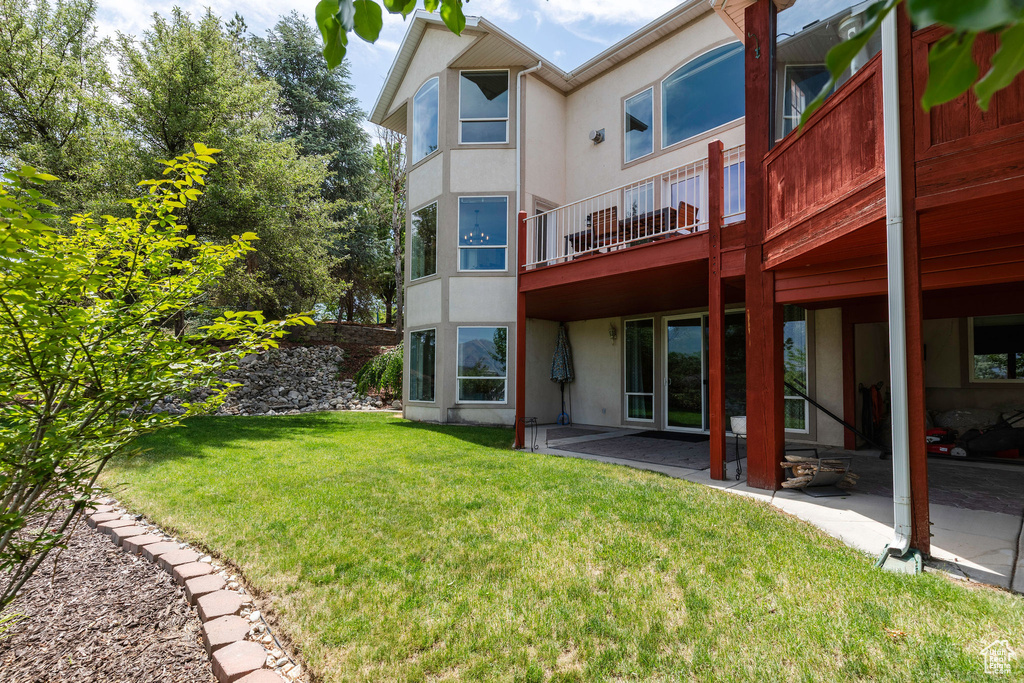Back of property with stucco siding, a patio area, and a yard