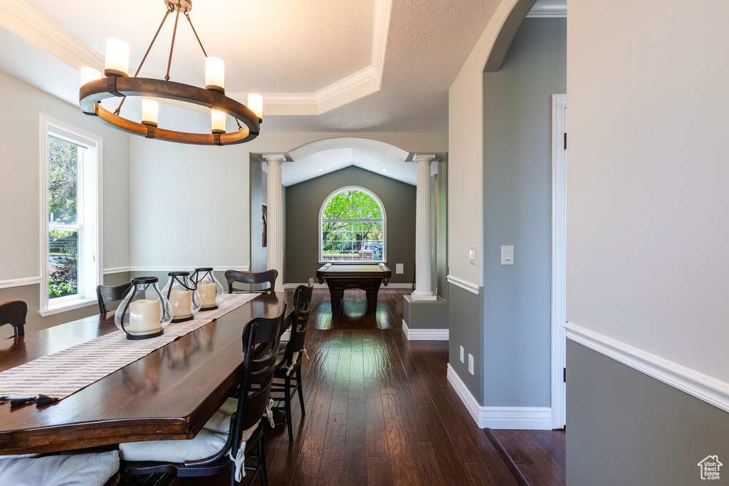 Dining area featuring ornate columns, arched walkways, dark wood-style flooring, and pool table