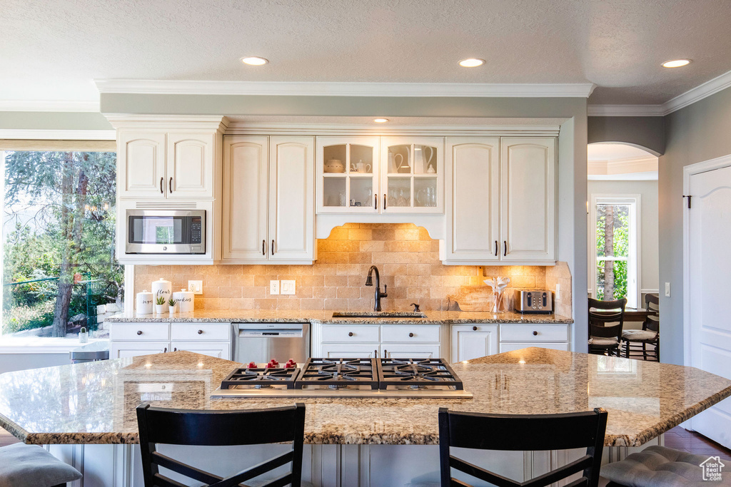 Kitchen featuring appliances with stainless steel finishes, a breakfast bar area, arched walkways, light stone counters, and recessed lighting