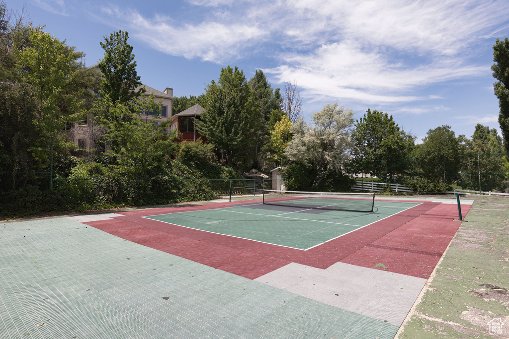 View of tennis court featuring community basketball court and view of wooded area