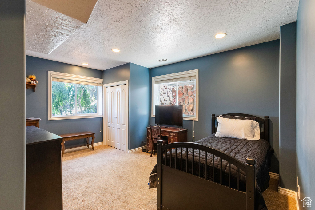 Bedroom with carpet floors, a textured ceiling, an office area, a closet, and recessed lighting
