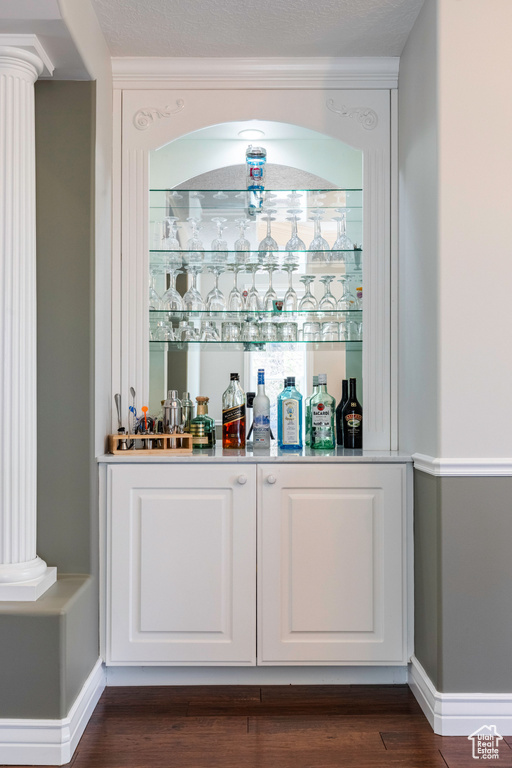 Indoor dry bar with dark wood-type flooring and ornate columns