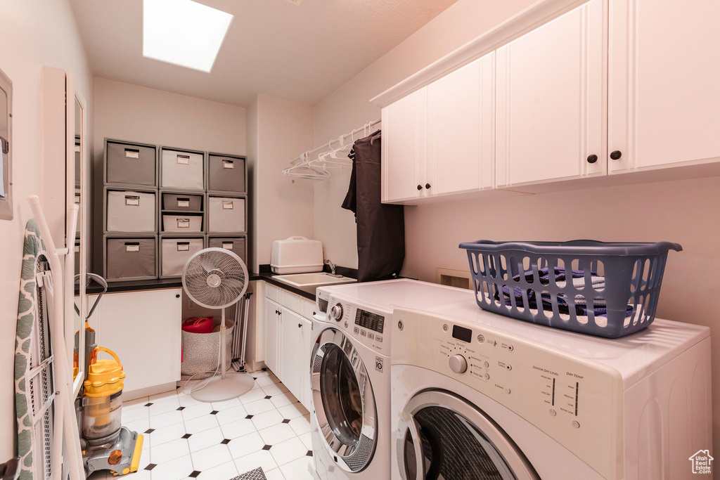 Washroom with cabinet space, washing machine and clothes dryer, and light flooring