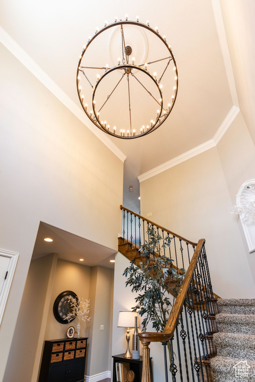 Staircase featuring a high ceiling, ornamental molding, a chandelier, and recessed lighting