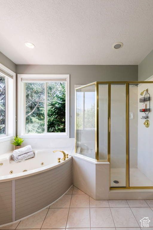 Bathroom featuring a tub with jets, a stall shower, a textured ceiling, tile patterned floors, and recessed lighting