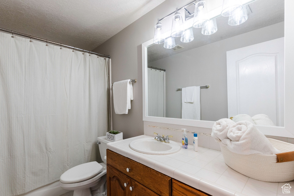 Bathroom featuring vanity, a textured ceiling, and a shower with curtain
