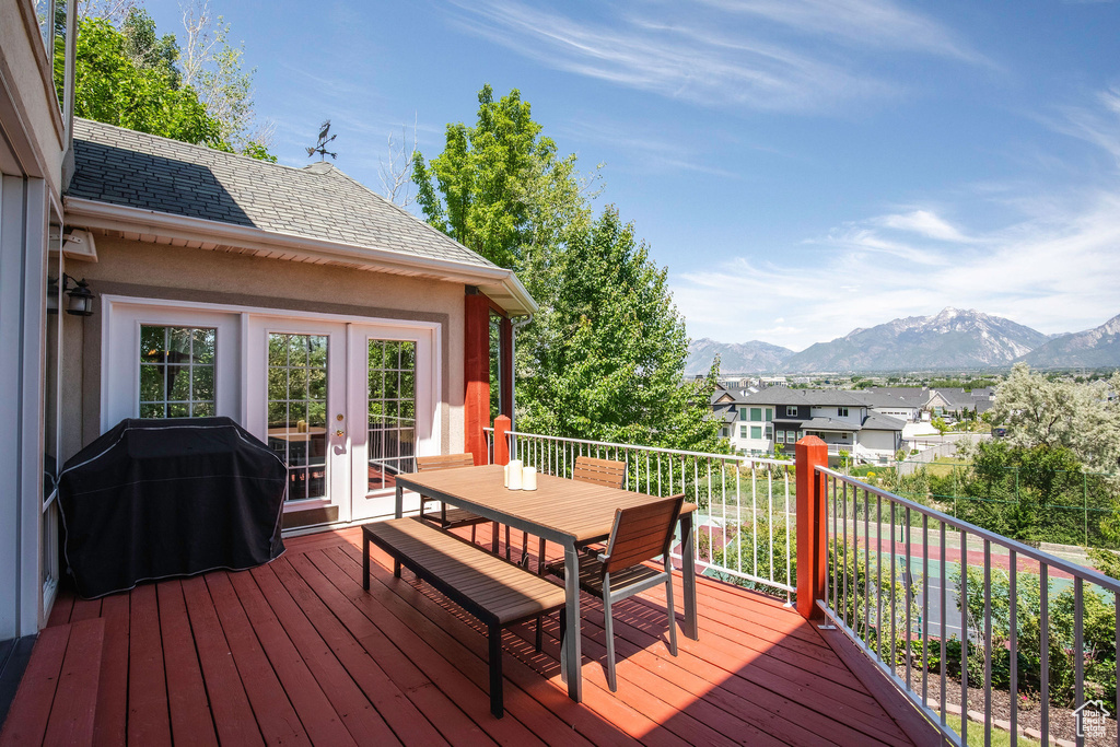 Wooden deck with french doors, a mountain view, outdoor dining space, grilling area, and a residential view