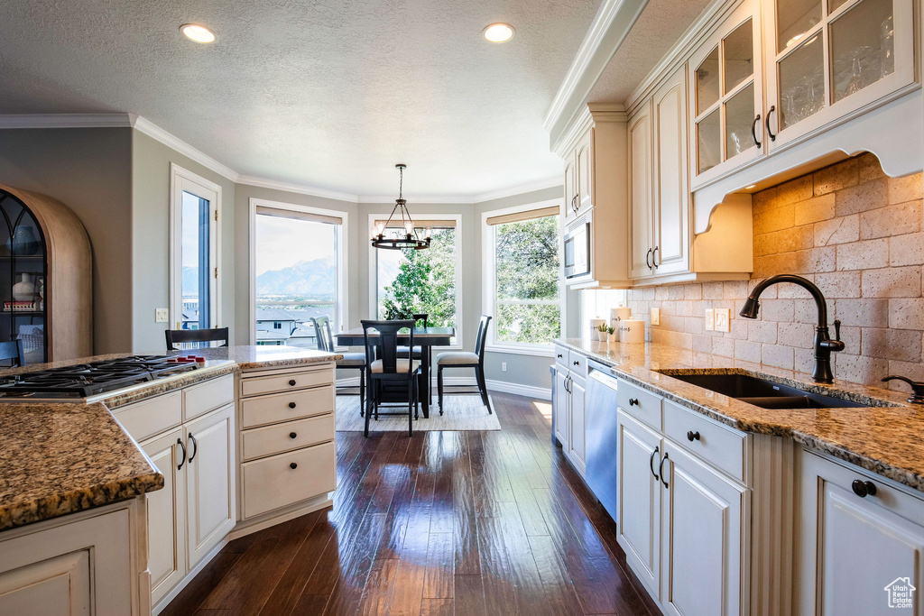 Kitchen featuring appliances with stainless steel finishes, glass insert cabinets, dark wood-style floors, stone counters, and a textured ceiling