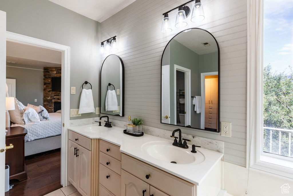 Ensuite bathroom featuring double vanity and wood finished floors