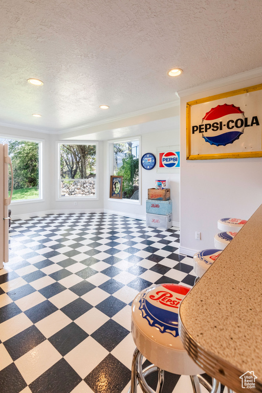 Interior space featuring tile patterned floors, recessed lighting, a textured ceiling, and ornamental molding