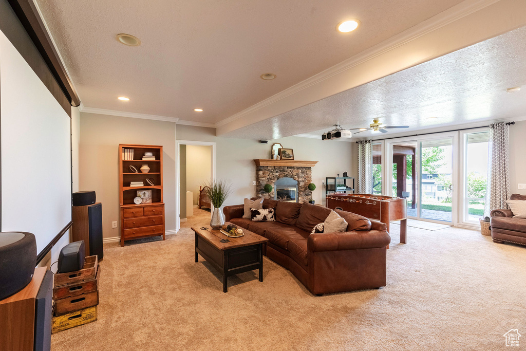 Living area featuring light carpet, a stone fireplace, recessed lighting, crown molding, and ceiling fan