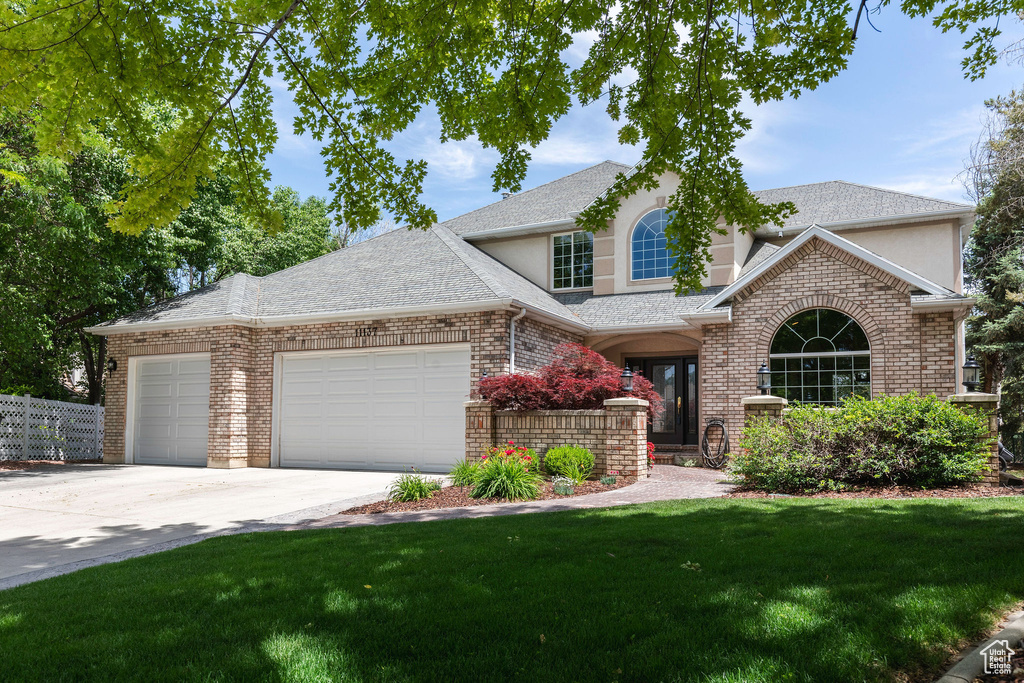 View of front facade featuring an attached garage, stucco siding, driveway, and a shingled roof