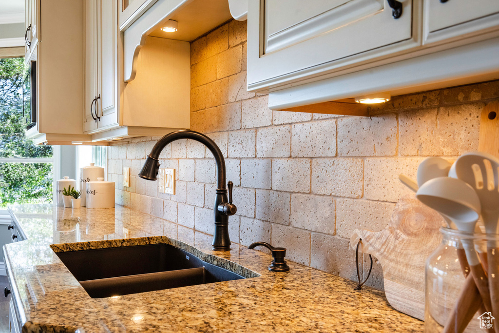 Kitchen view of cream cabinets, backsplash, and light stone counters