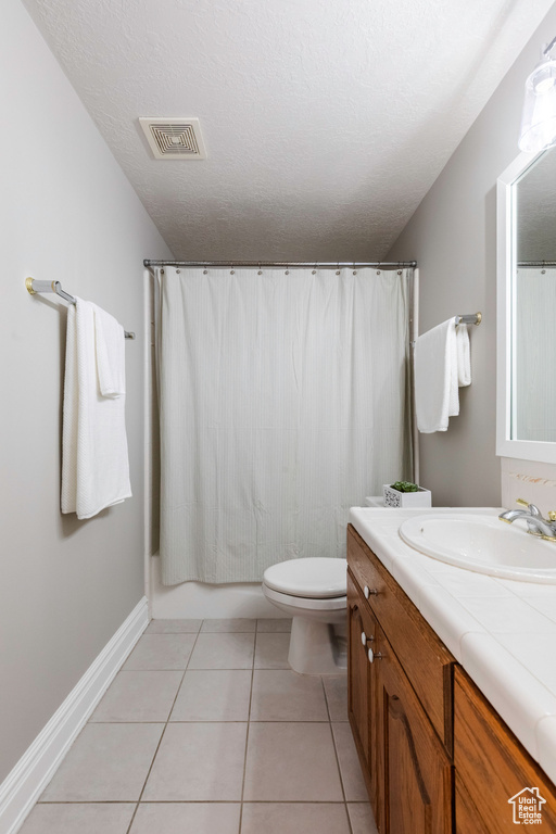 Bathroom featuring vanity, tile patterned flooring, shower / bath combination with curtain, and a textured ceiling