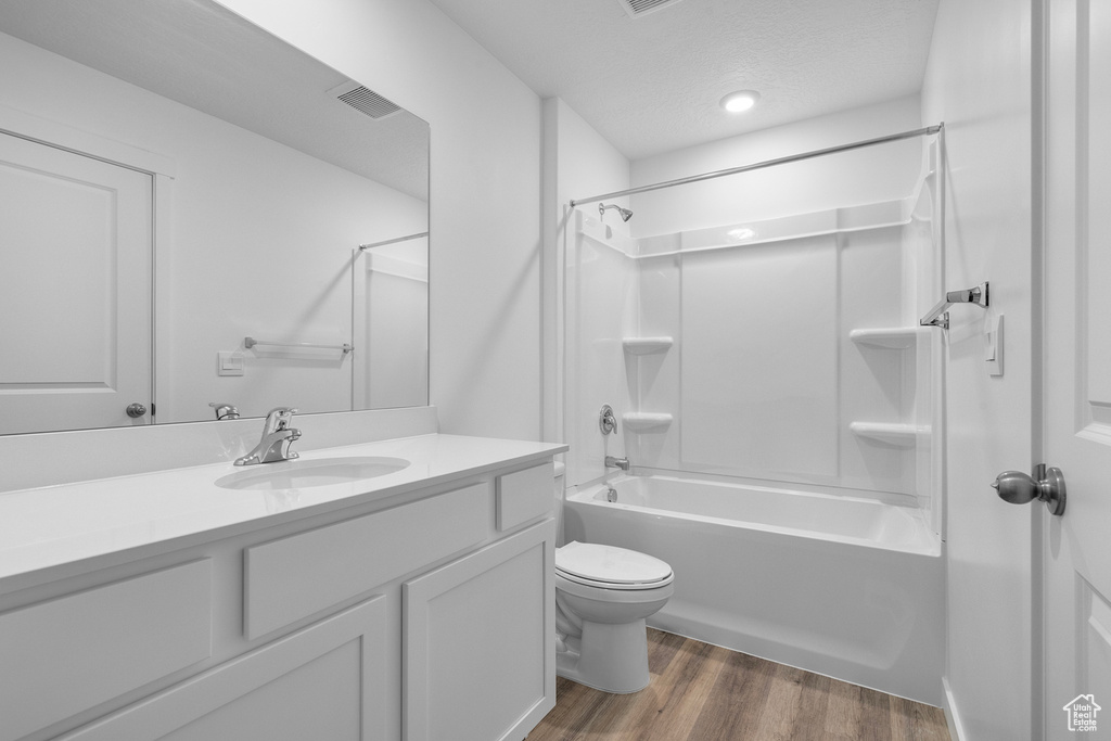 Full bathroom with wood finished floors, vanity, tub / shower combination, toilet, and visible vents