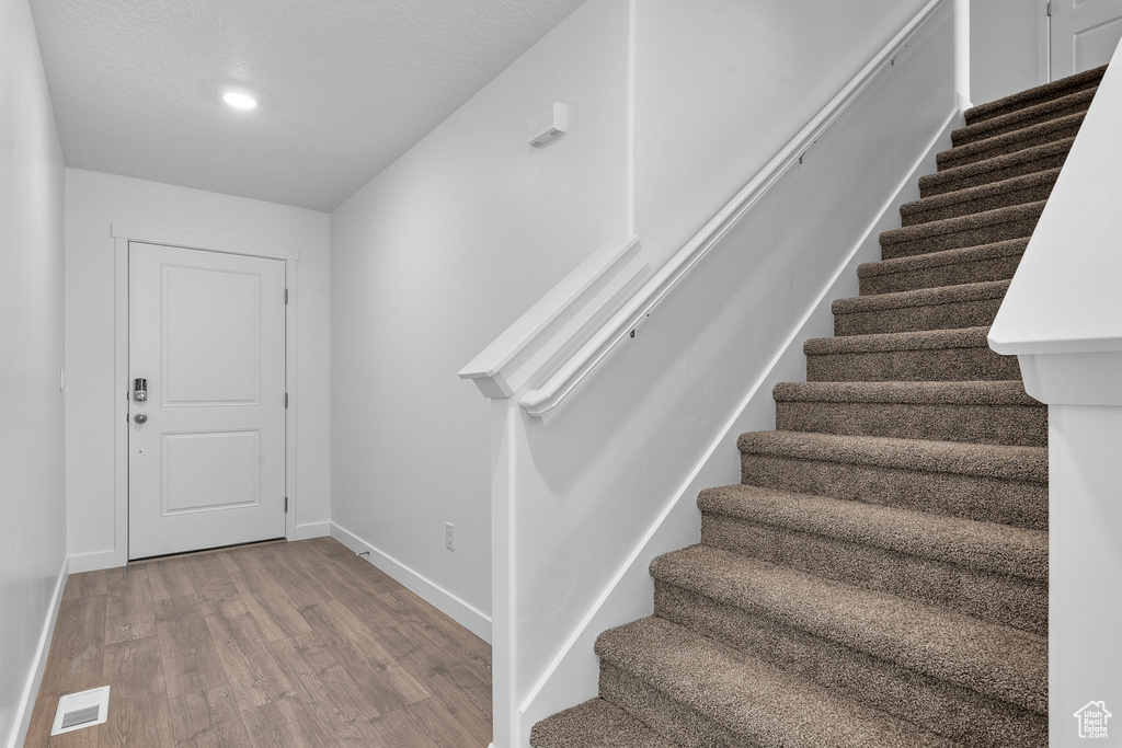 Stairs with recessed lighting, wood finished floors, visible vents, and baseboards