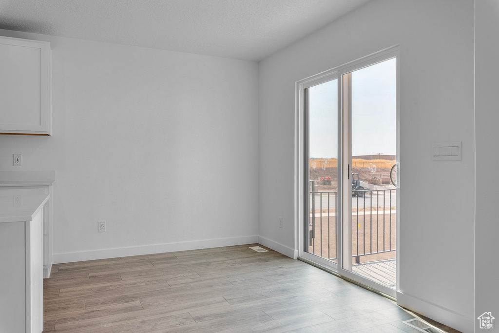 Unfurnished dining area with a wealth of natural light, light wood-style floors, and baseboards