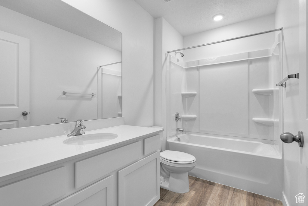 Full bathroom featuring wood finished floors, vanity,  shower combination, and toilet