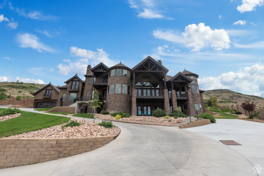 View of front of house featuring curved driveway, a chimney, and a balcony