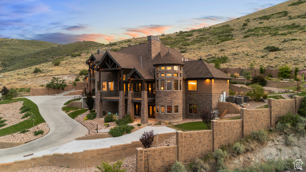 View of front of property featuring a balcony, stone siding, a chimney, and a mountain view