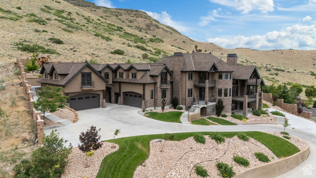 View of front of home featuring a balcony, a chimney, stucco siding, and a mountain view