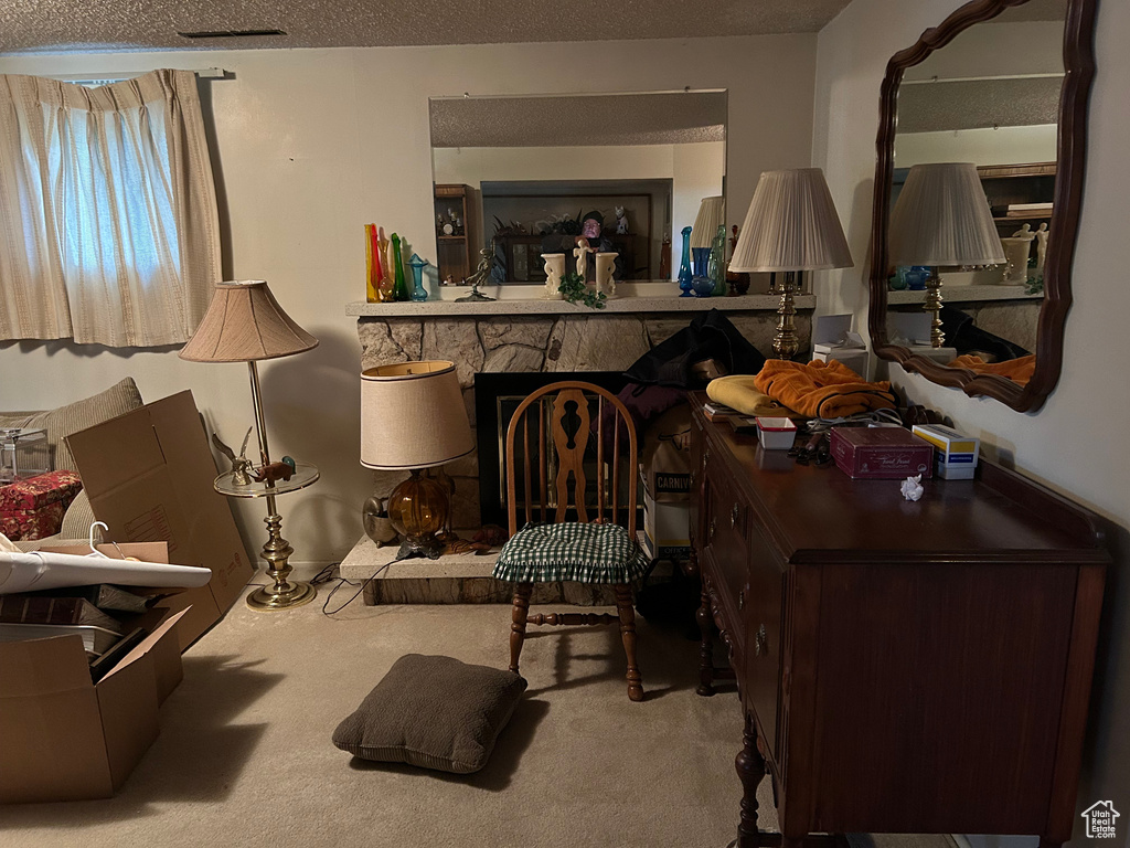 Living area featuring a fireplace, visible vents, carpet floors, and a textured ceiling