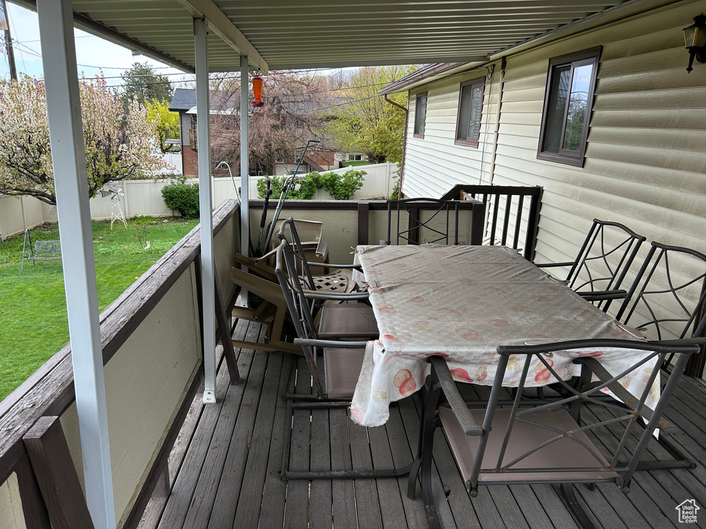 Wooden deck with a lawn, outdoor dining space, and a fenced backyard