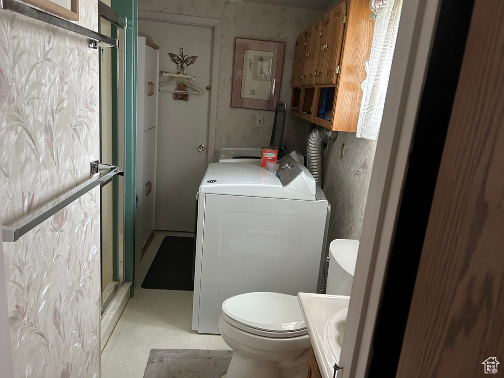 Bathroom featuring vanity, a shower stall, washer / clothes dryer, and toilet