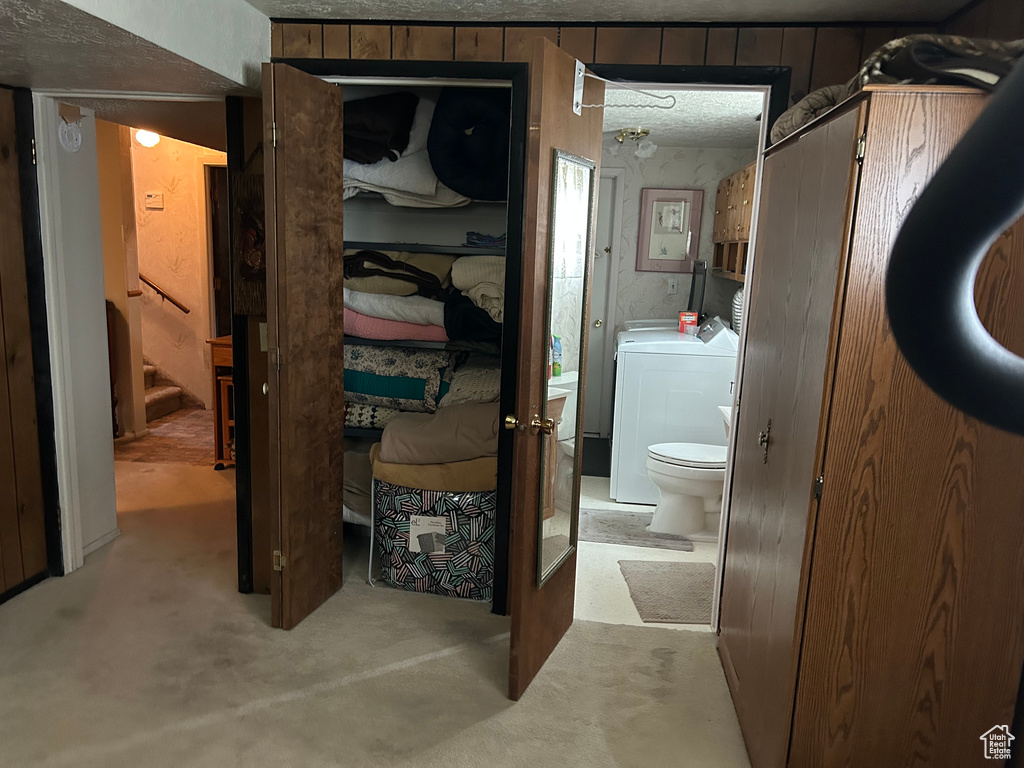 Bathroom with toilet, concrete flooring, and washer / dryer