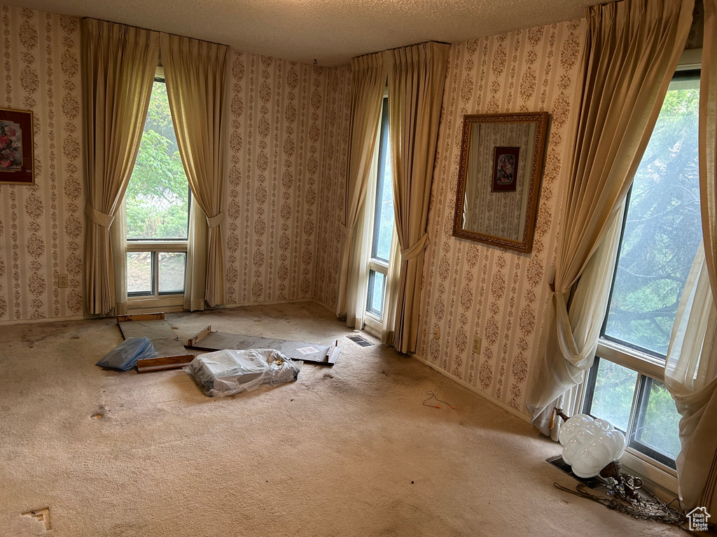 Interior space featuring a textured ceiling, wallpapered walls, and plenty of natural light