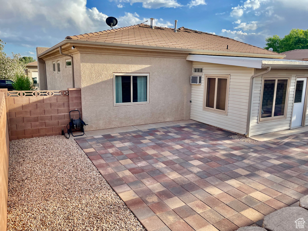 Back of property with fence, a patio, and a wall mounted AC