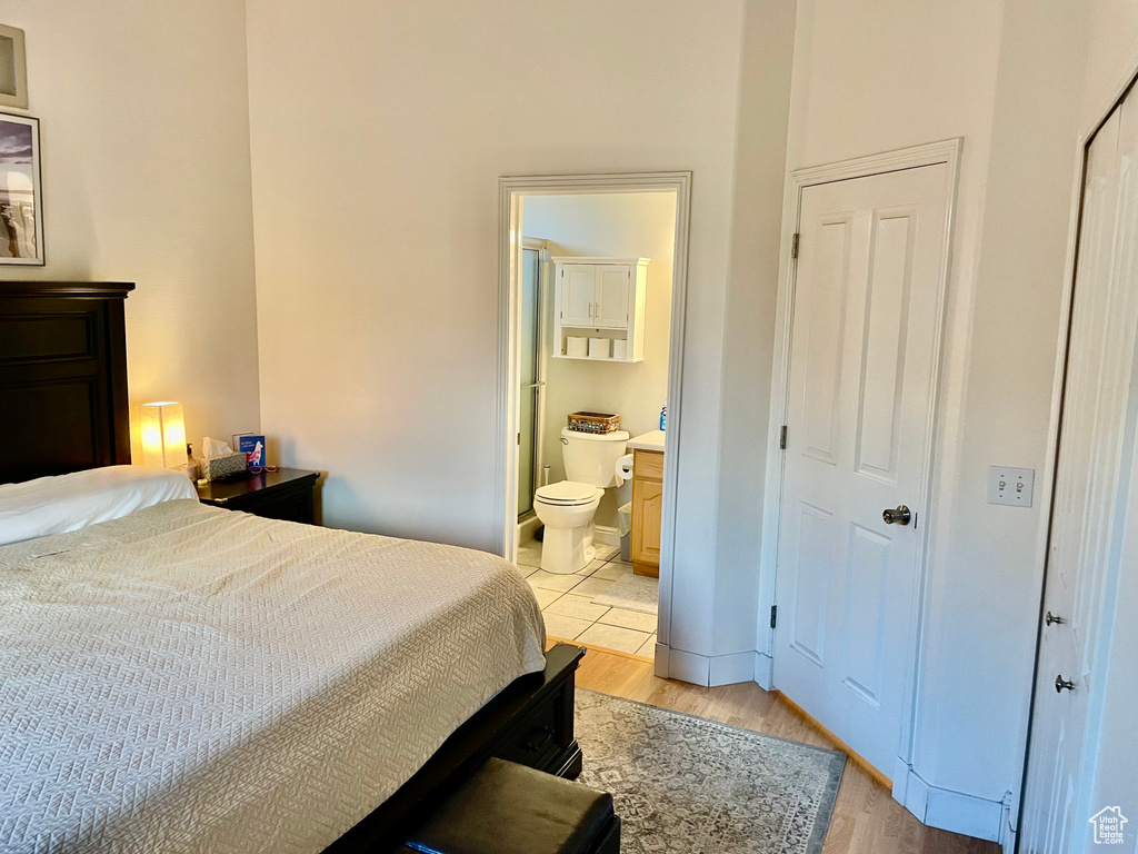 Bedroom featuring light wood-style flooring, ensuite bath, and baseboards