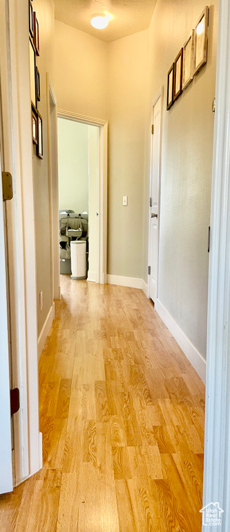Corridor with light wood-style flooring and baseboards