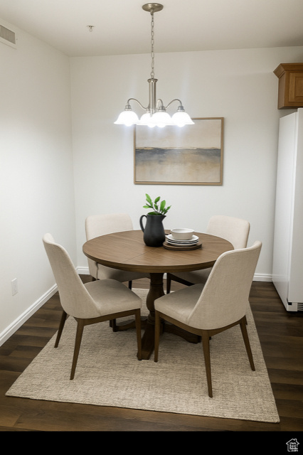 Dining room featuring a chandelier and dark wood-style flooring
