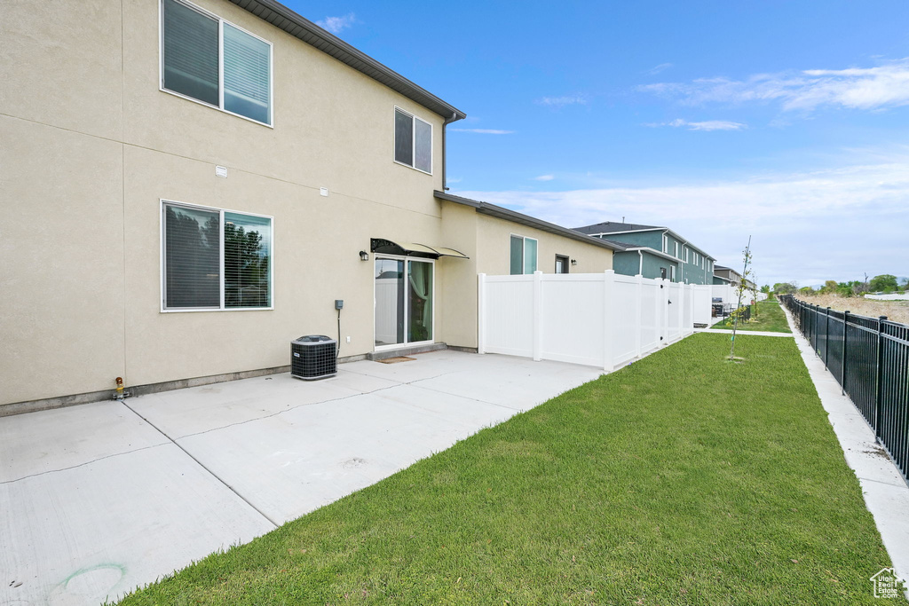 Back of property with a yard, stucco siding, fence, and a patio